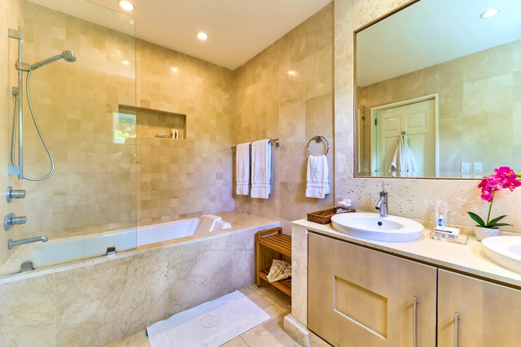 A tiled bathroom with a bathtub, glass shower screen, and vanity.