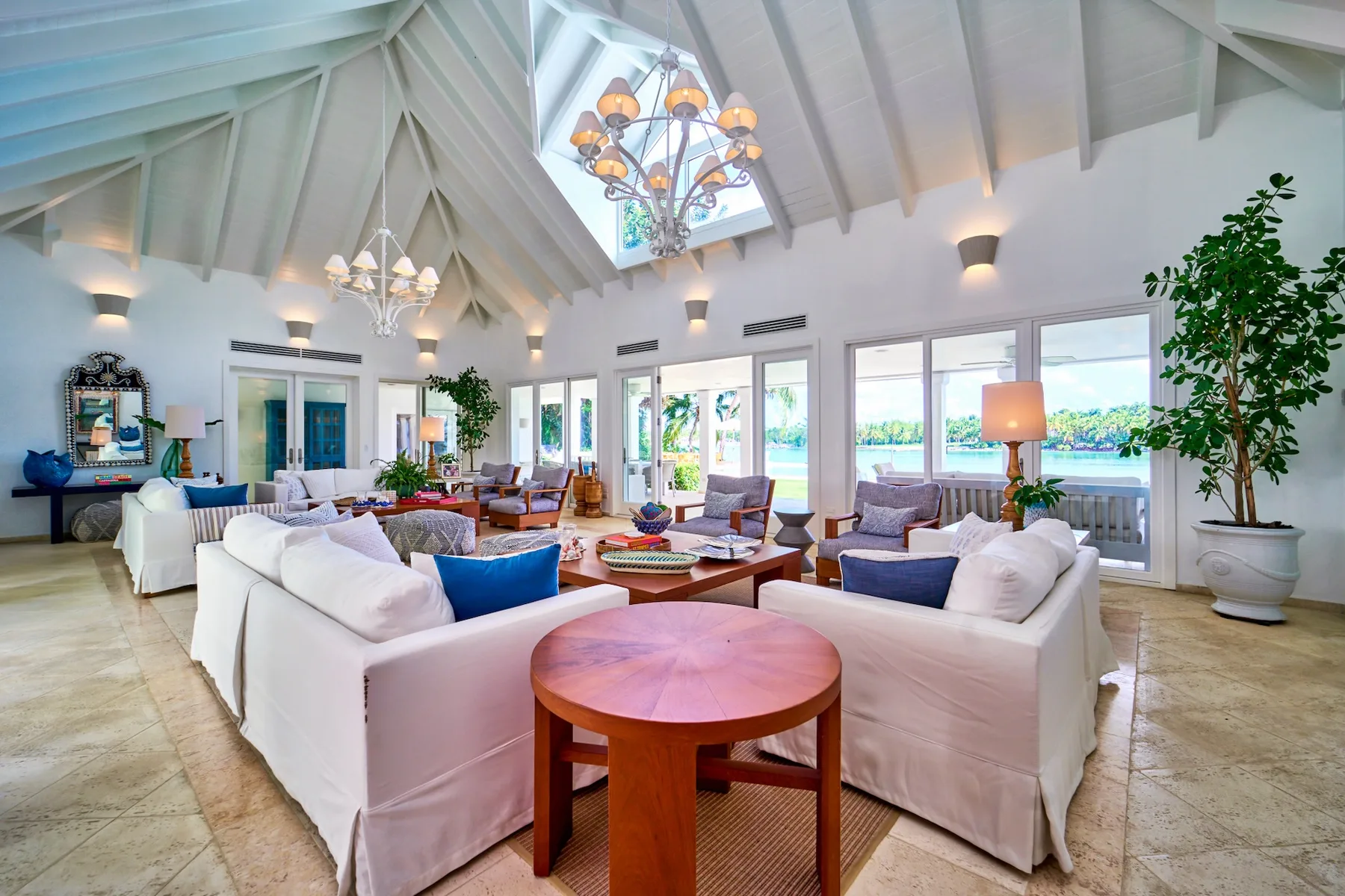 A bright living room with white seating arranged around a wooden coffee table.