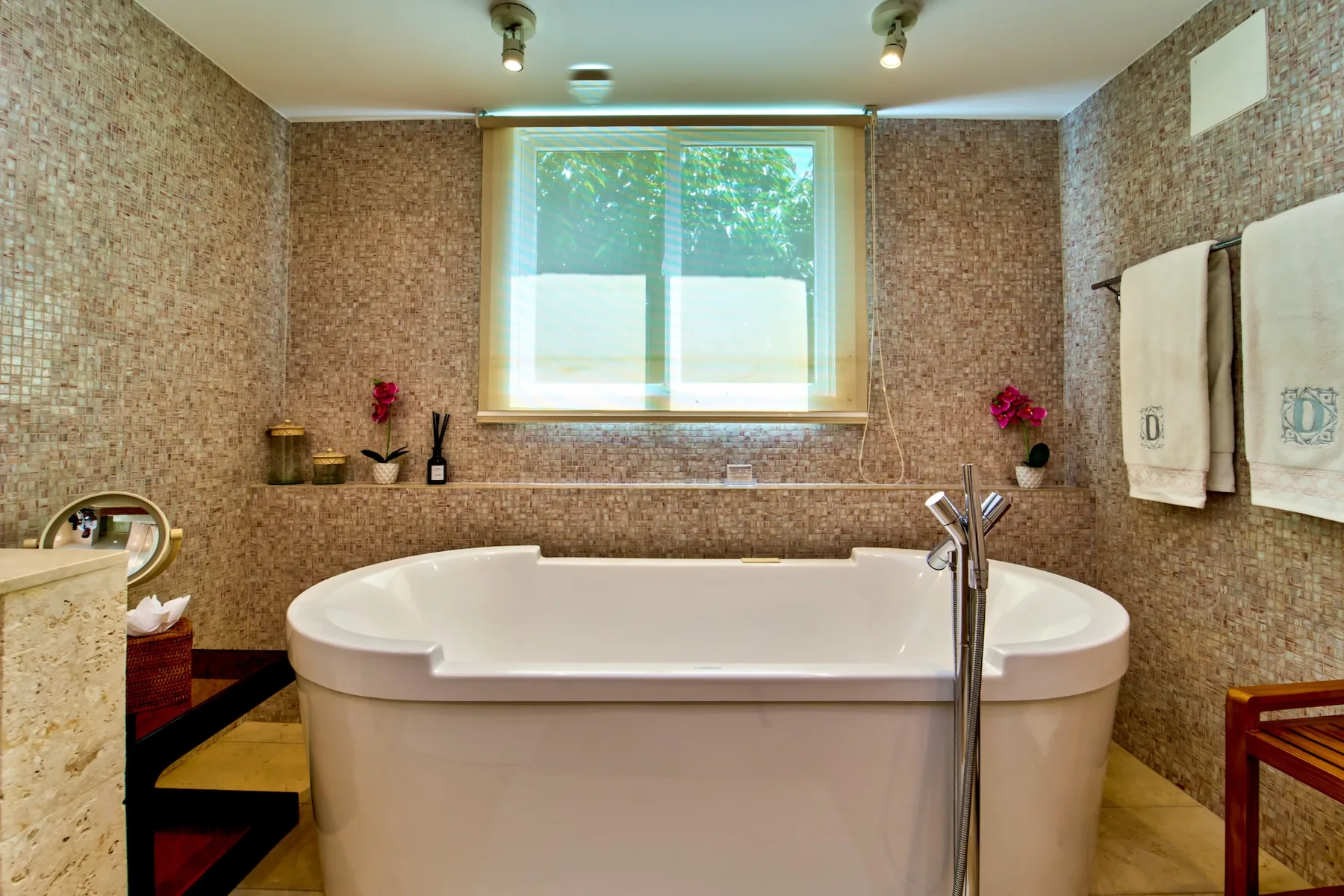 A bathroom with a large bathtub beneath a window.