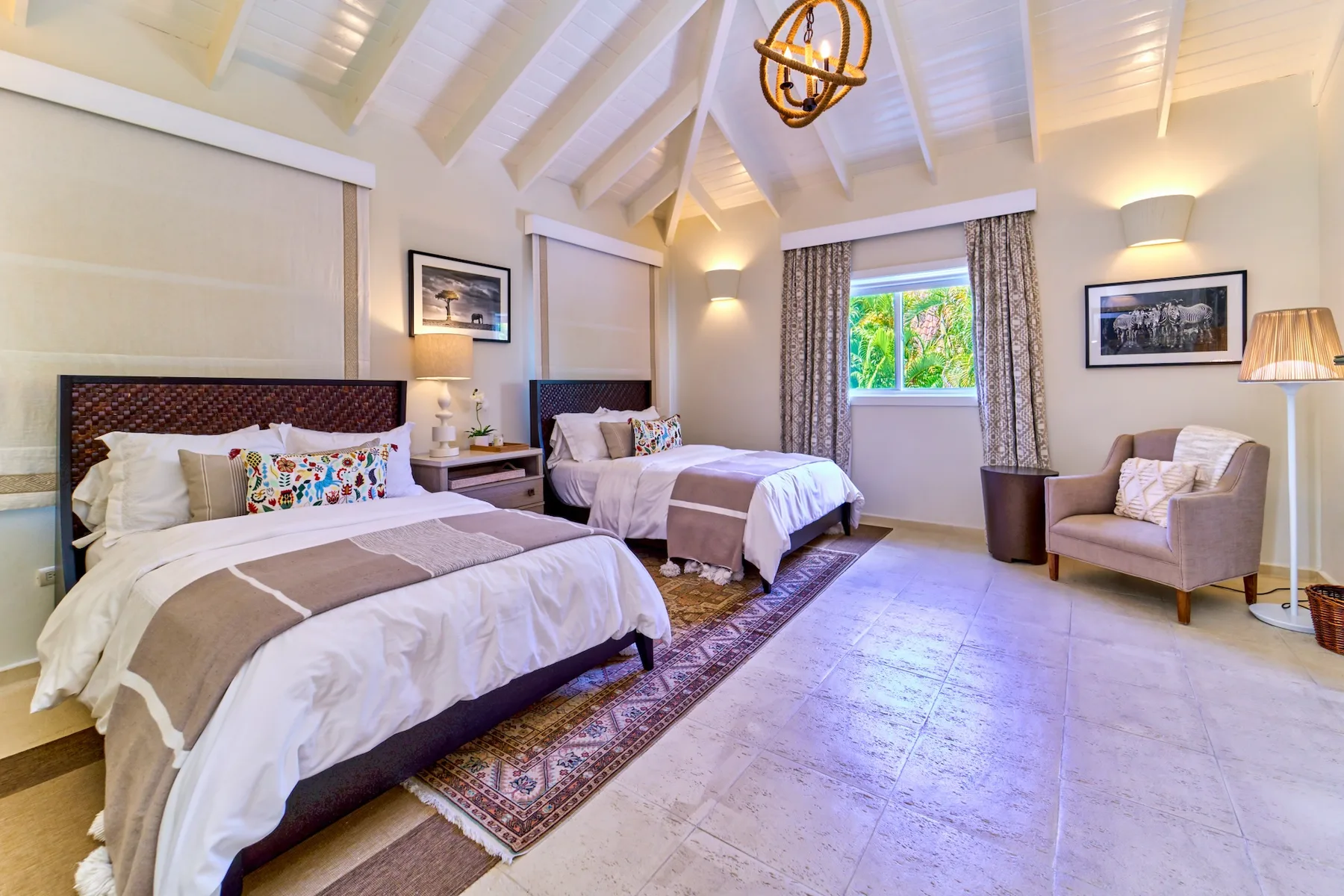 A bedroom with two beds, a window, and an armchair.