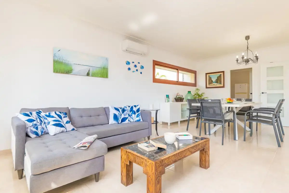 A bright living and dining area with a gray sofa and a wooden coffee table.