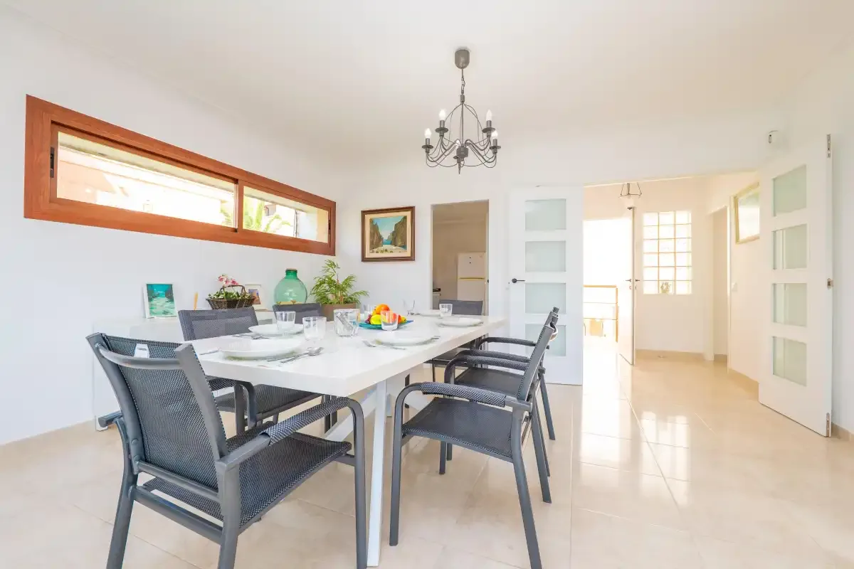 A bright dining room with a table and chairs beside an open doorway.