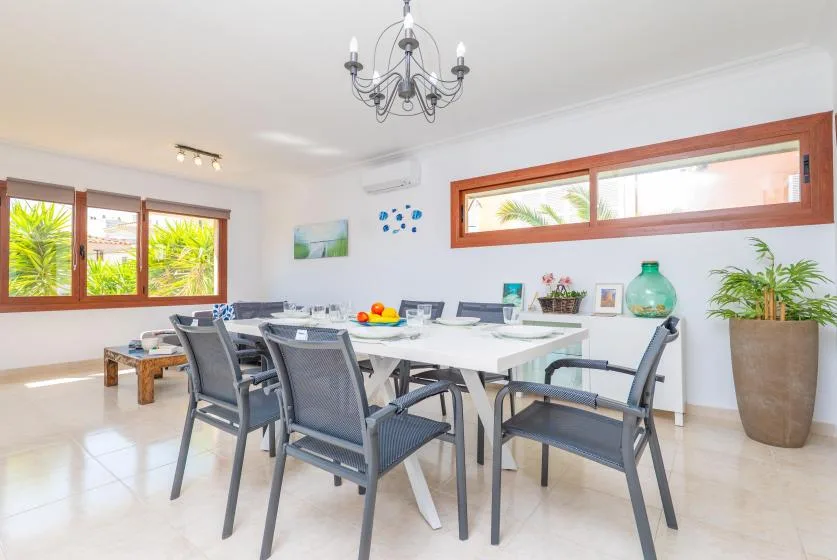 A bright dining area with a long table, several chairs, and large windows.