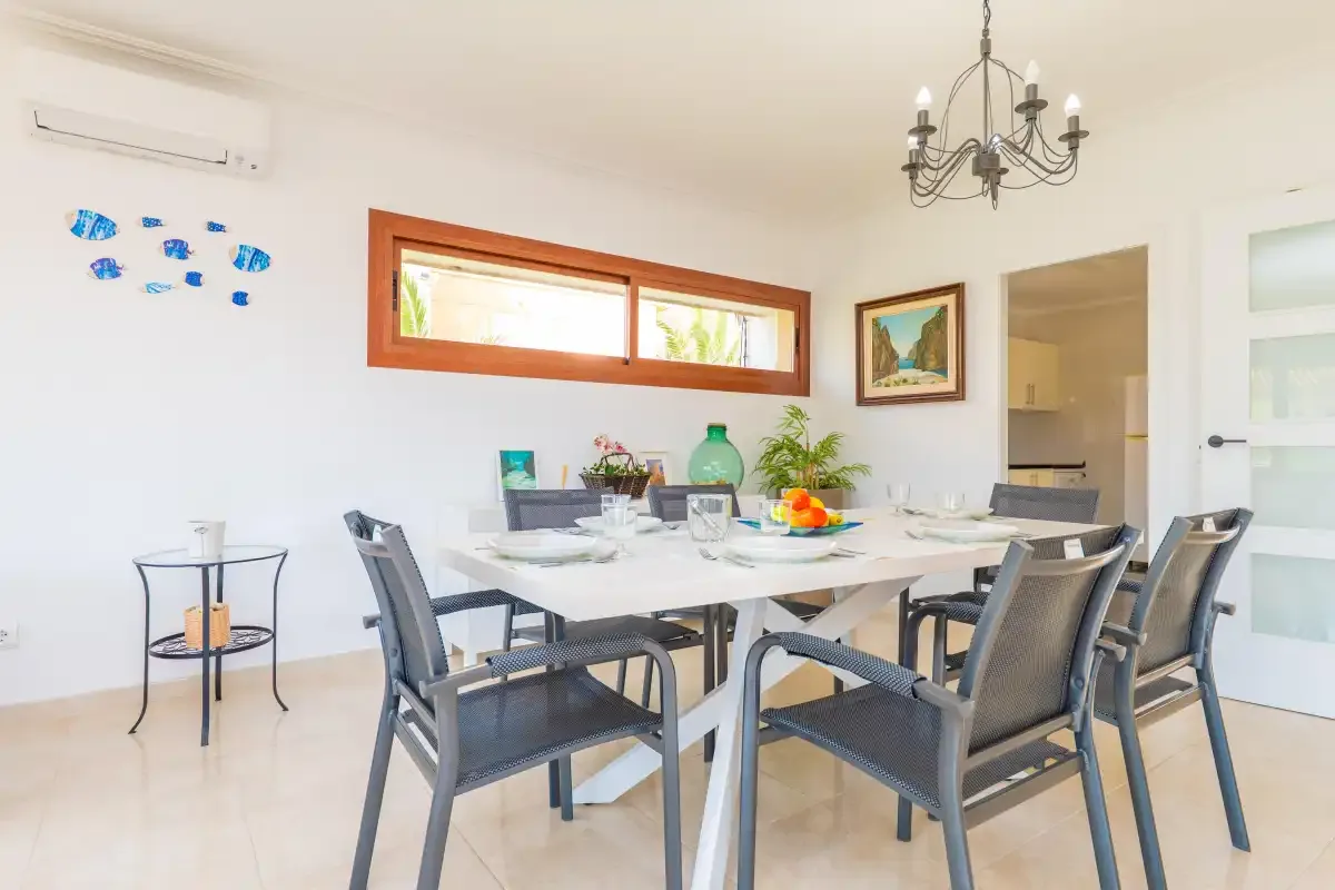 A bright dining room with a table set beside a long window.