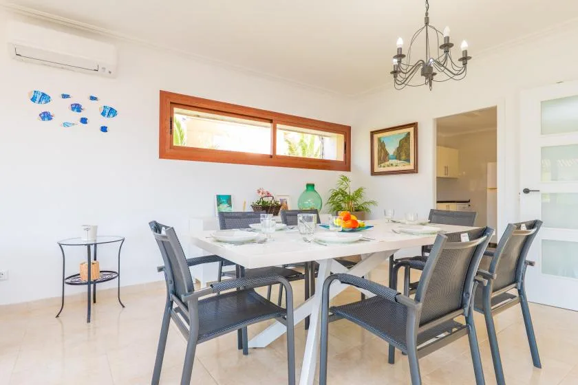 A bright dining room with a long table and dark woven seating.