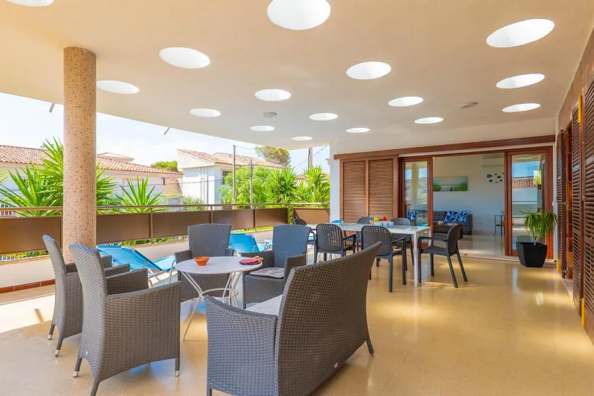 A covered outdoor dining area with tables, chairs, and greenery along the railing.