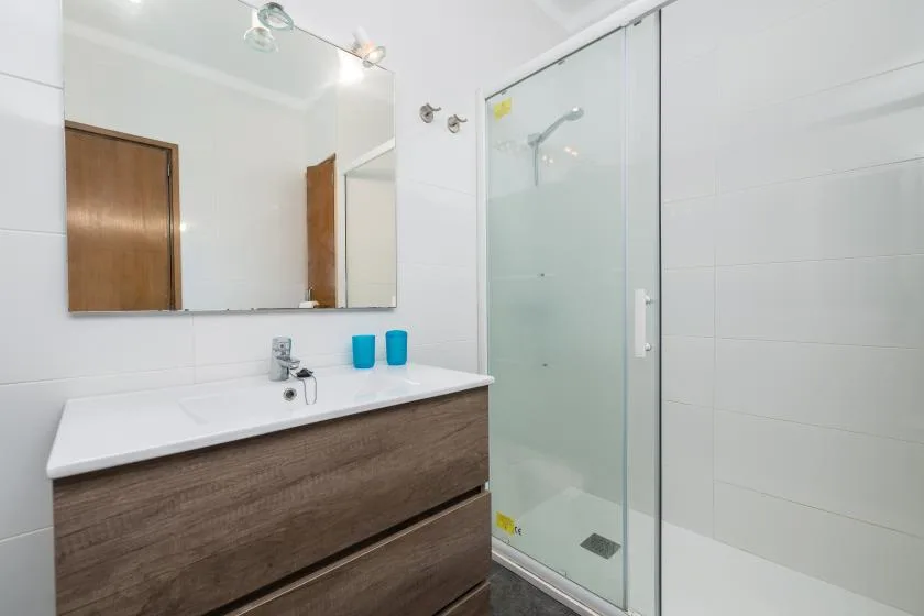 A bright bathroom with a long vanity and a glass shower.