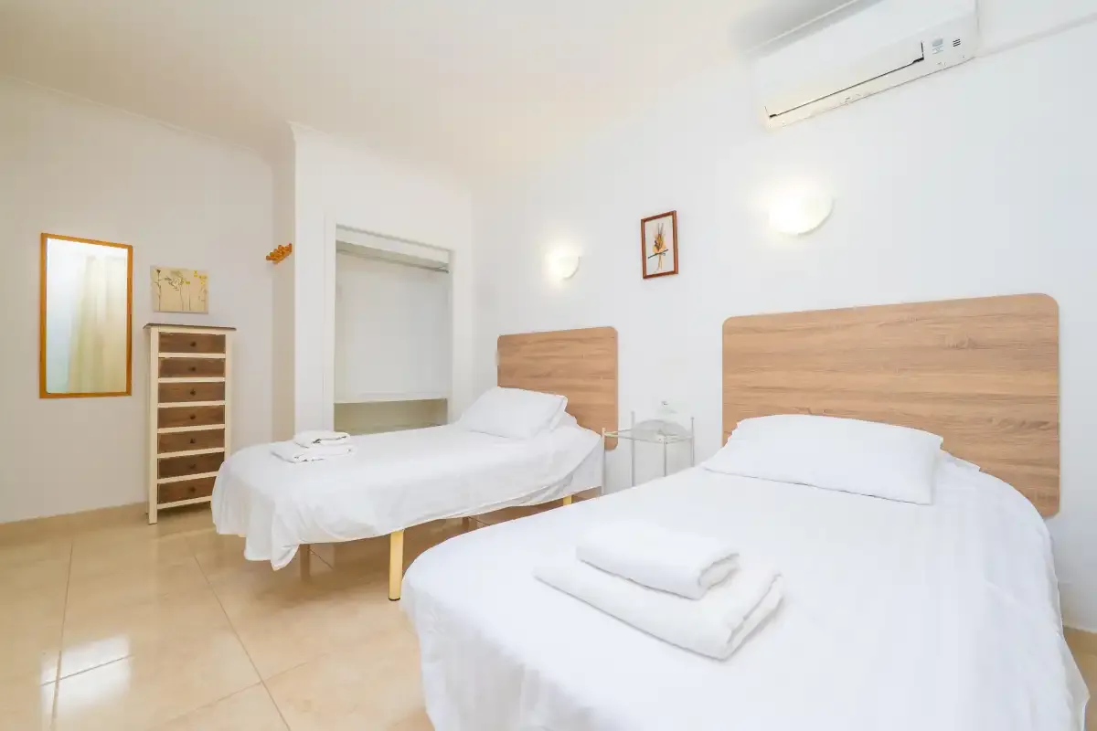 A bright bedroom with two beds dressed in white linens.