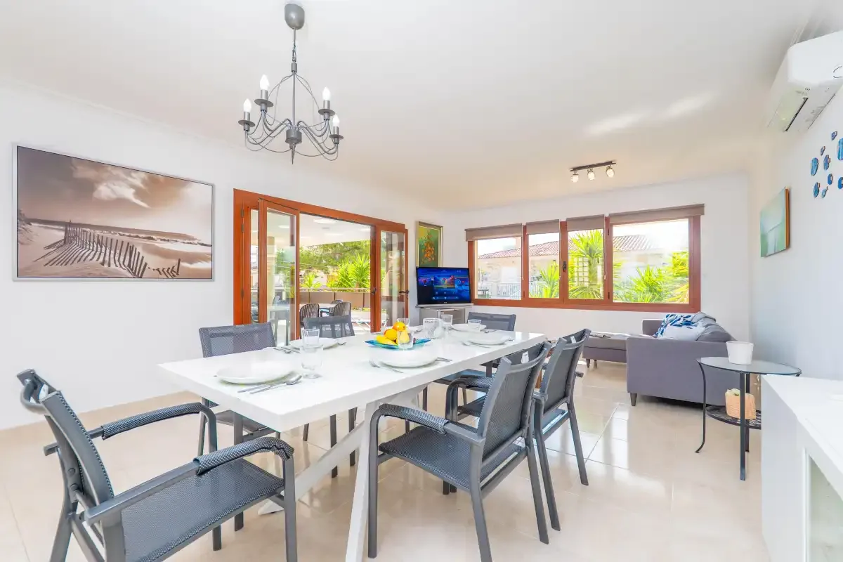 A bright living and dining room with a long table and seating by the windows.