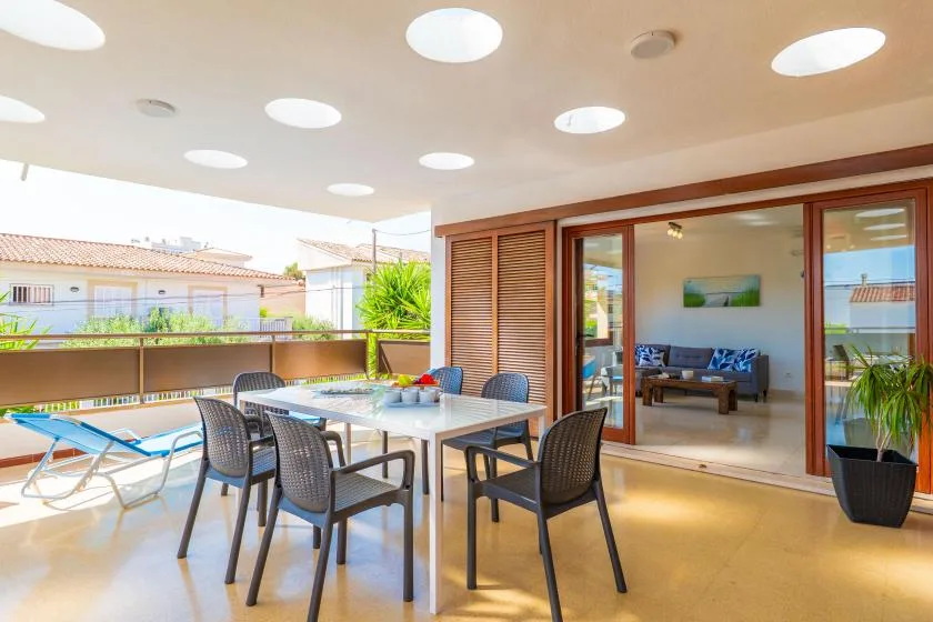 A covered patio with a dining table and seating opens onto a living room.