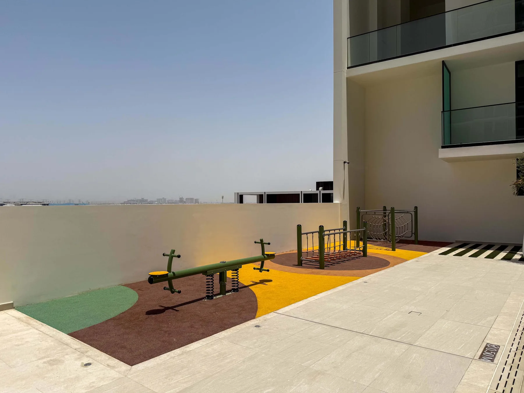 An outdoor exercise area with fitness equipment beside a modern building.