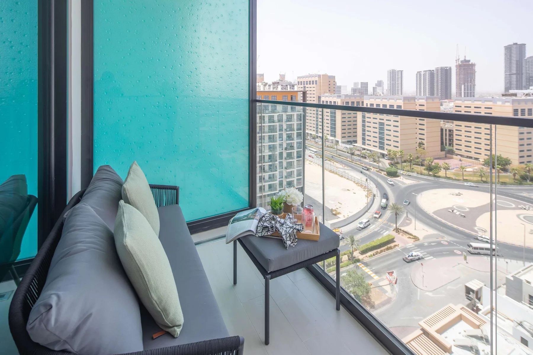 A living room seating area beside floor-to-ceiling windows overlooks city streets.