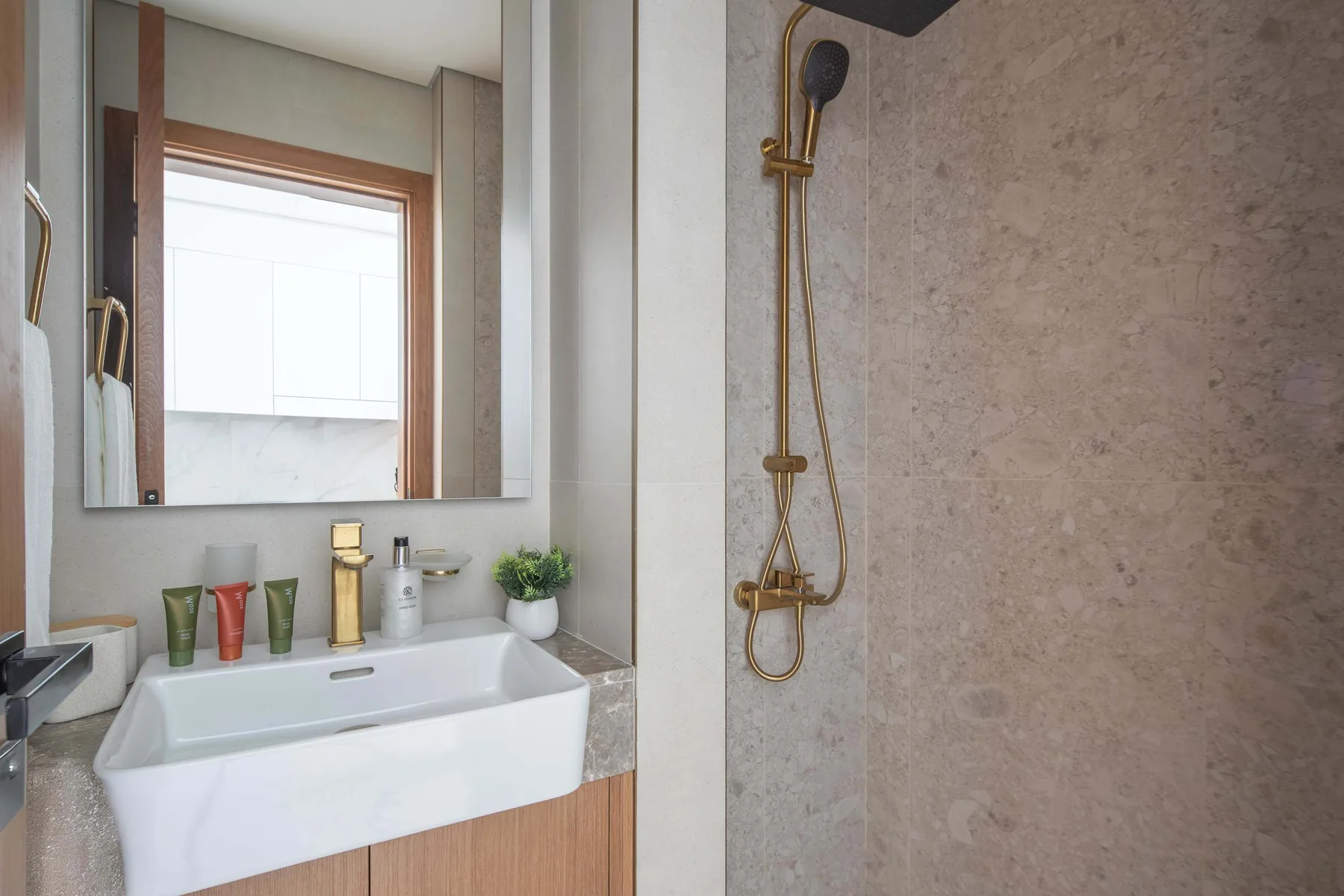 A bathroom vanity with a sink sits beside a shower with a handheld fixture.