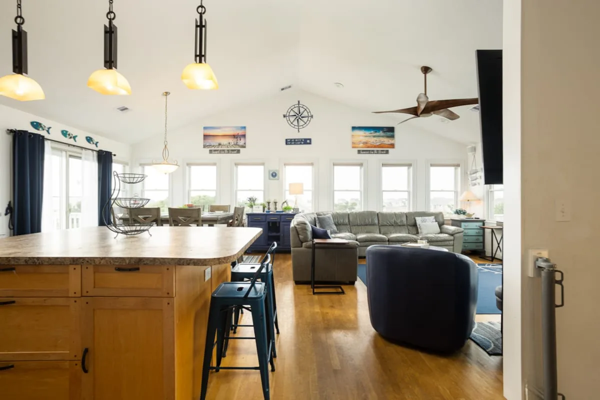Una sala de estar y cocina diáfanas y luminosas, con una isla grande y asientos.