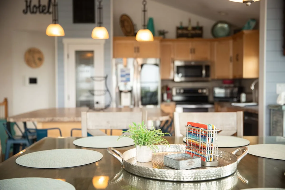 Una zona de comedor en la cocina con mesa, asientos y armarios de madera.