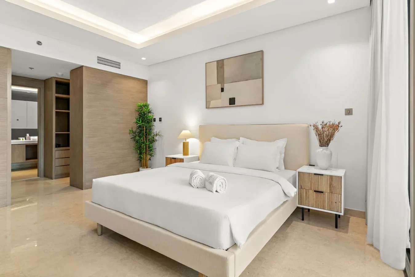 Un dormitorio con una cama bien tendida, mesitas de noche y arte enmarcado.