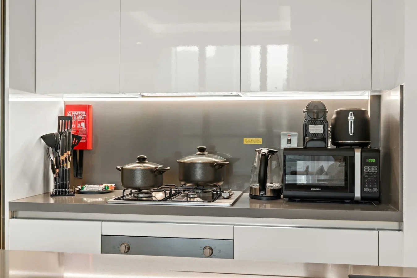 Una encimera de cocina moderna con estufa, utensilios de cocina y pequeños electrodomésticos.