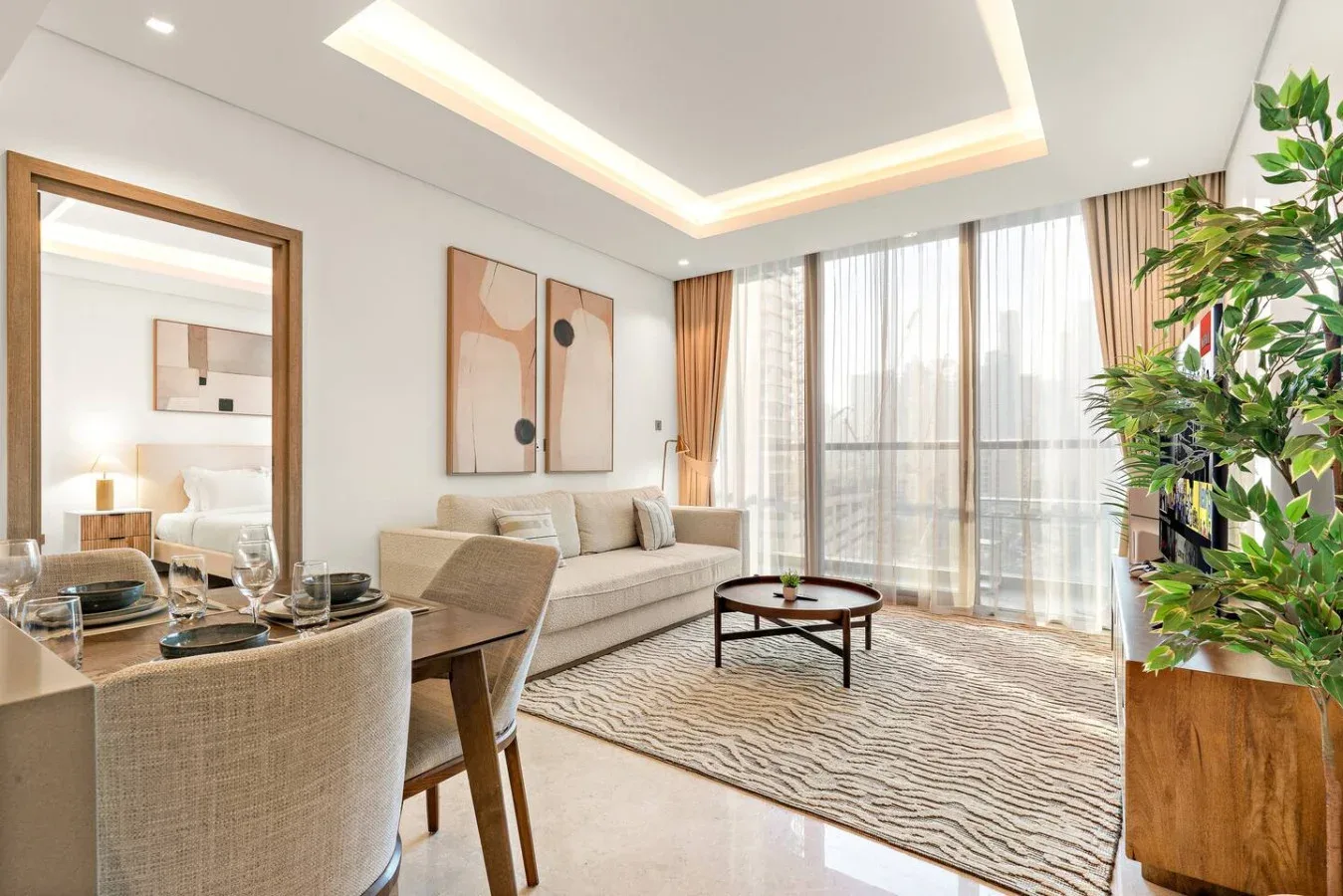 Una sala luminosa con sofá, mesa de comedor y ventanas altas.