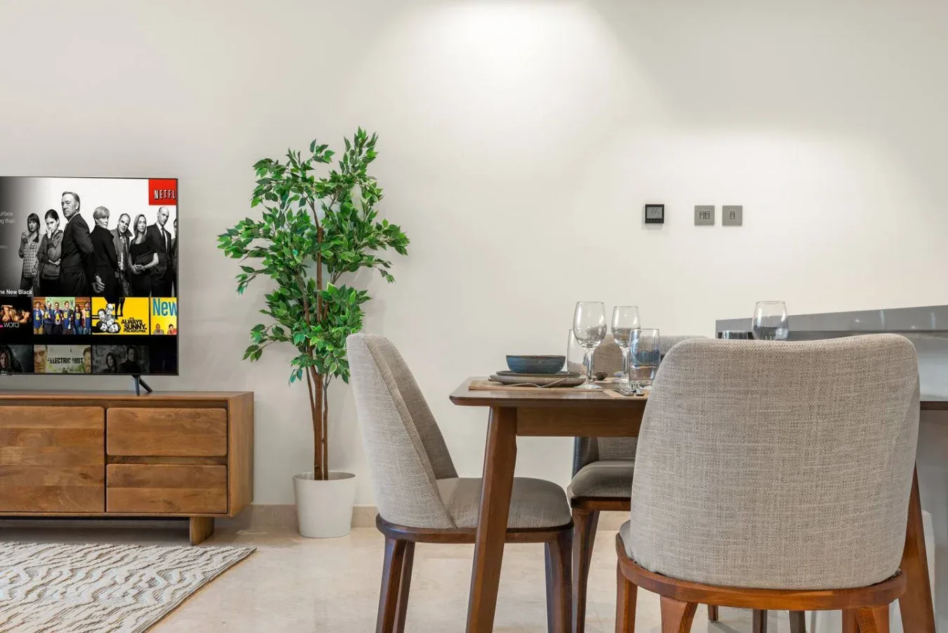Comedor con una mesa de madera y sillas junto a una planta en maceta.