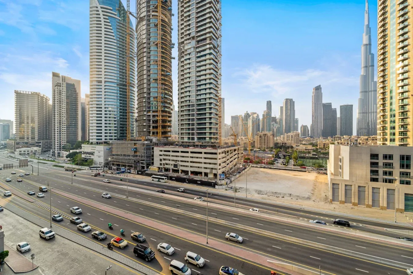 El horizonte urbano se alza tras edificios altos junto a una concurrida autopista de varios carriles.