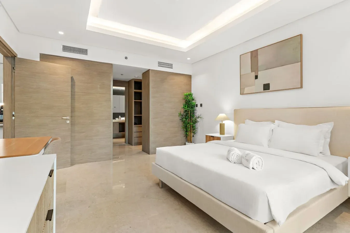 Un dormitorio luminoso con una cama bien tendida e iluminación empotrada en el techo.