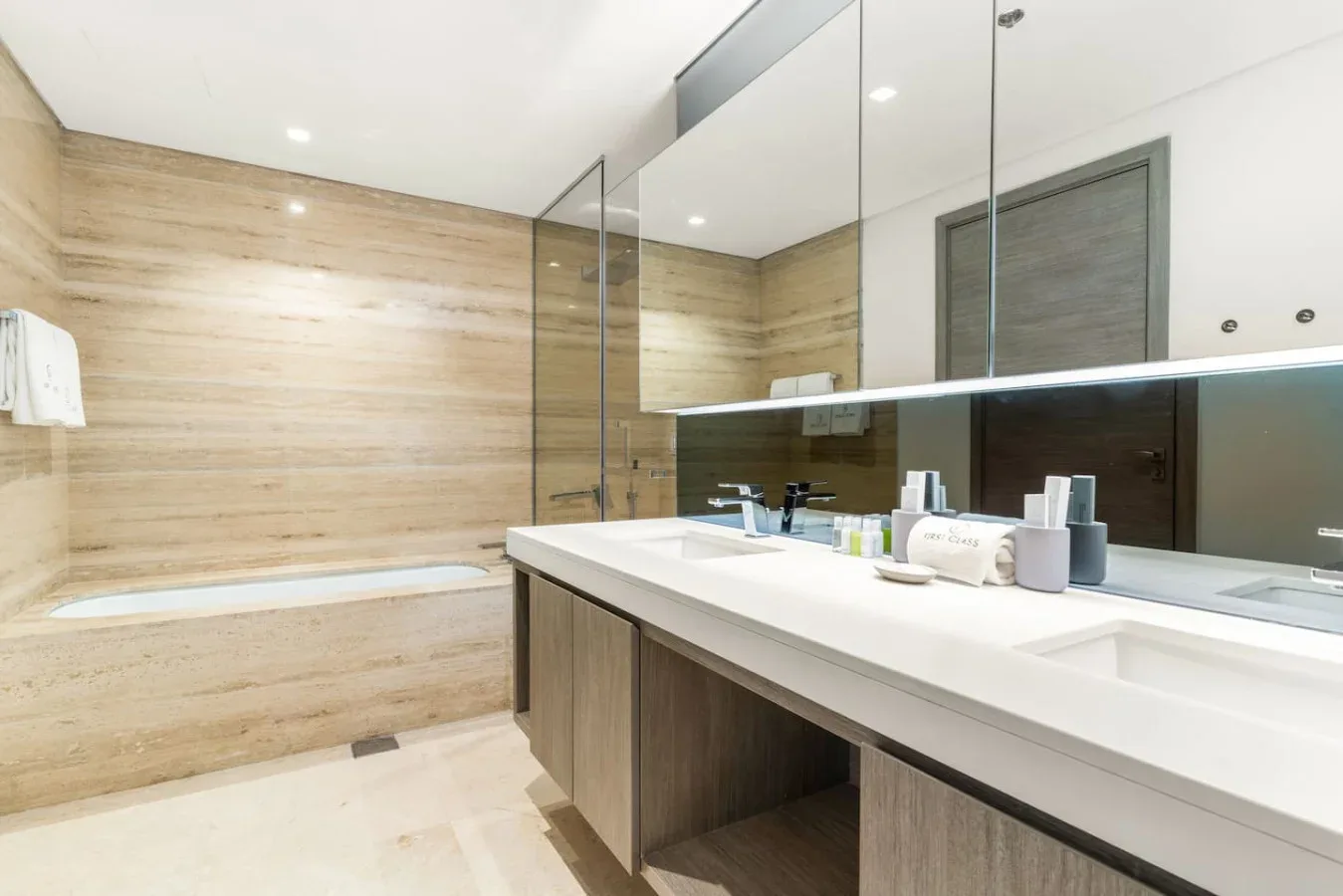 Un baño moderno con un lavabo largo y una bañera junto a la pared.