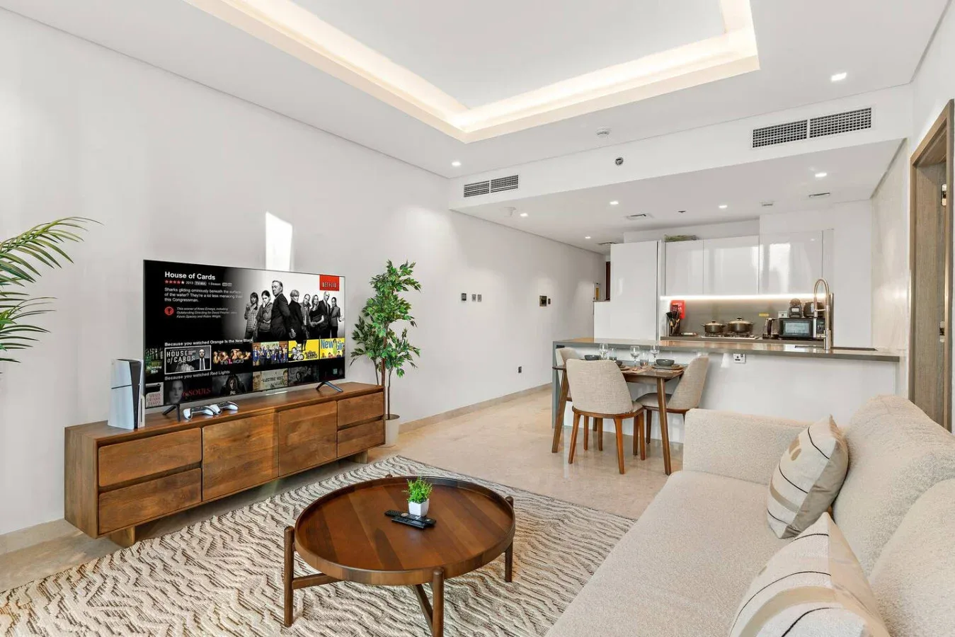 Una sala luminosa con televisión, asientos y un comedor.