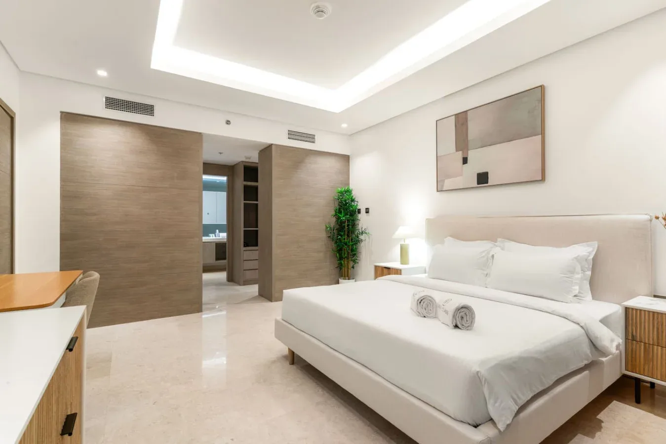 Un dormitorio luminoso con una cama bien arreglada y puertas de armario revestidas de madera.