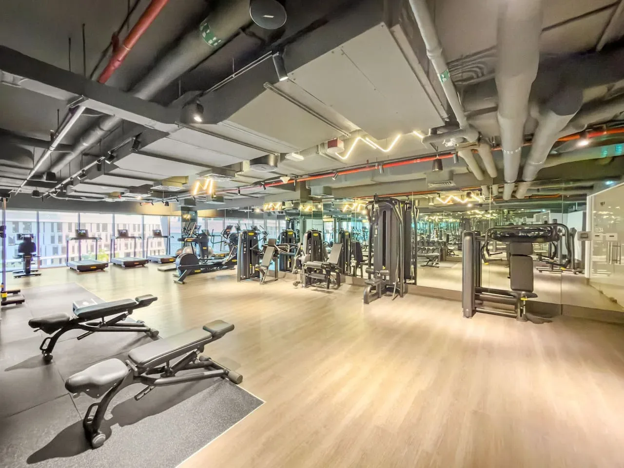 Un gimnasio amplio con máquinas de ejercicio y bancos de pesas.