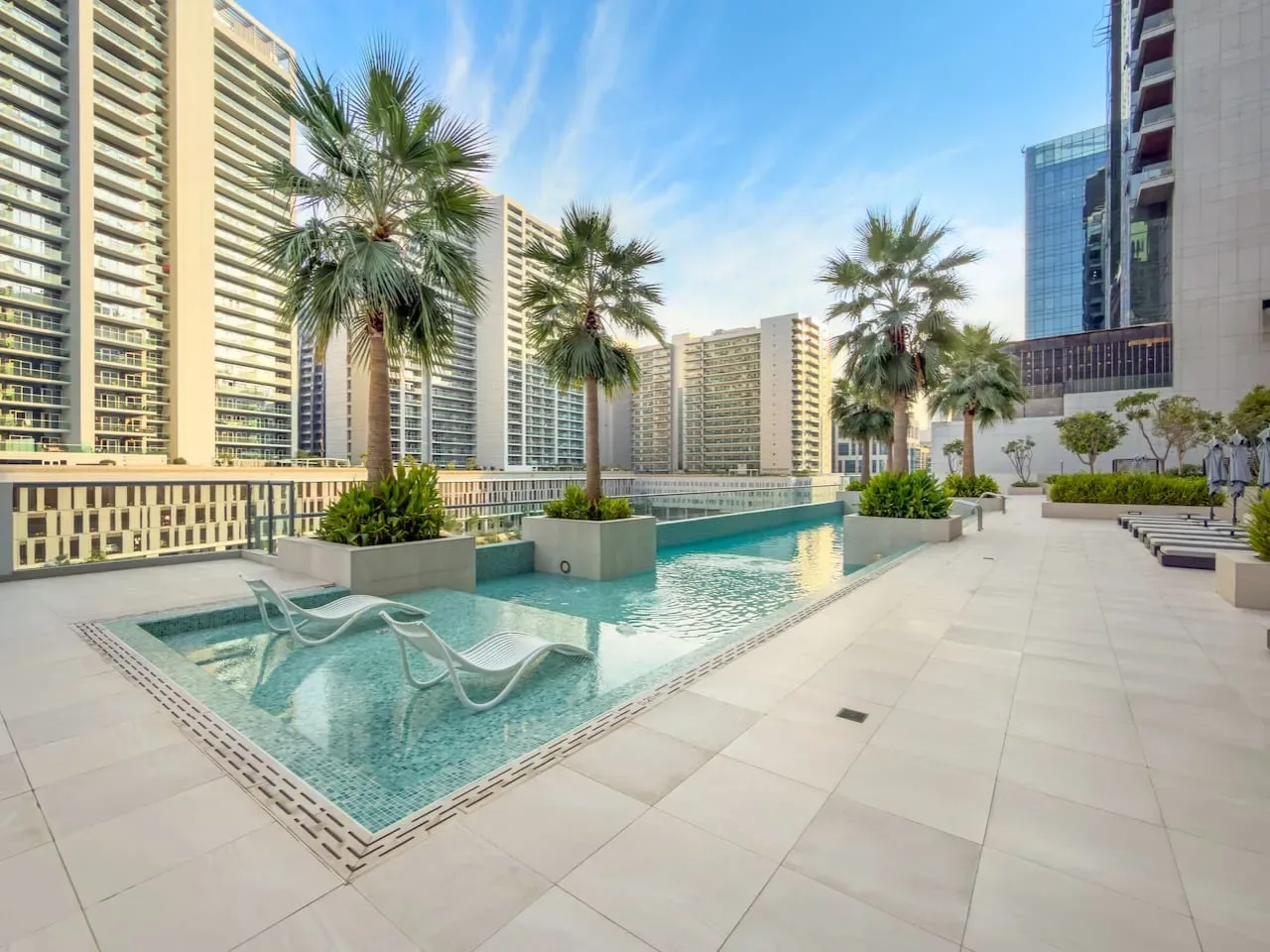 Una piscina al aire libre con palmeras y edificios altos al fondo.