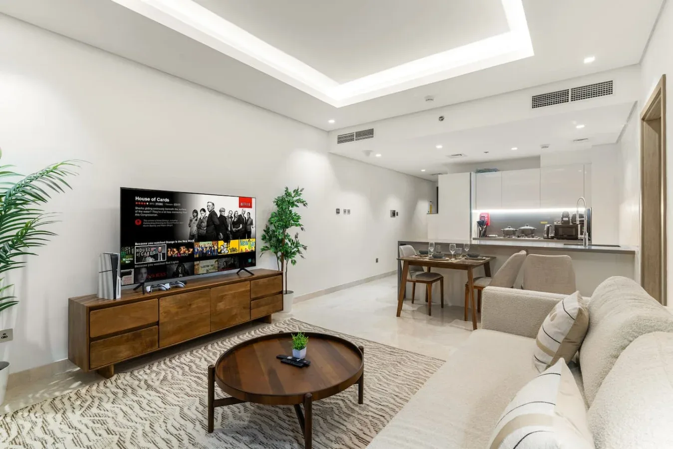 Una sala luminosa con televisor, asientos y una mesa de comedor.