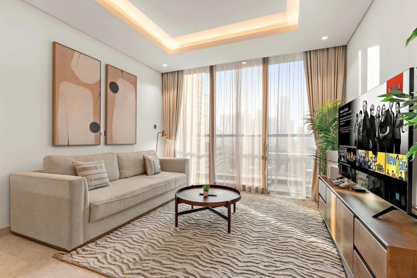 Una sala luminosa con asientos, una mesa de centro y grandes ventanas con cortinas.