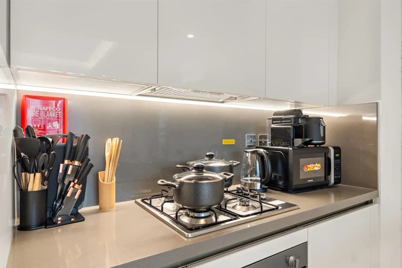 Una encimera de cocina moderna con una estufa de gas, ollas y pequeños electrodomésticos.
