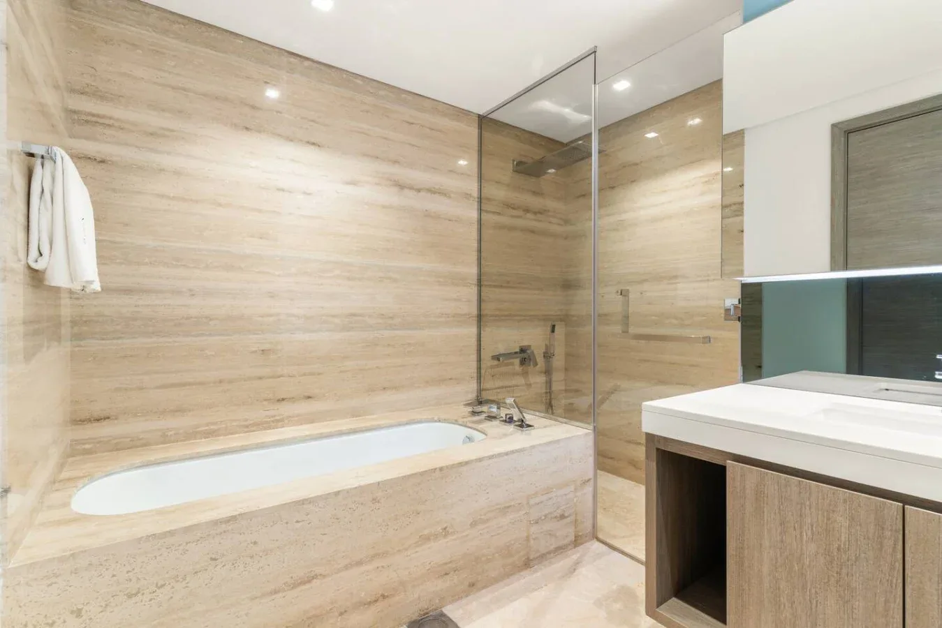 Un baño con bañera, mampara de vidrio y lavabo.