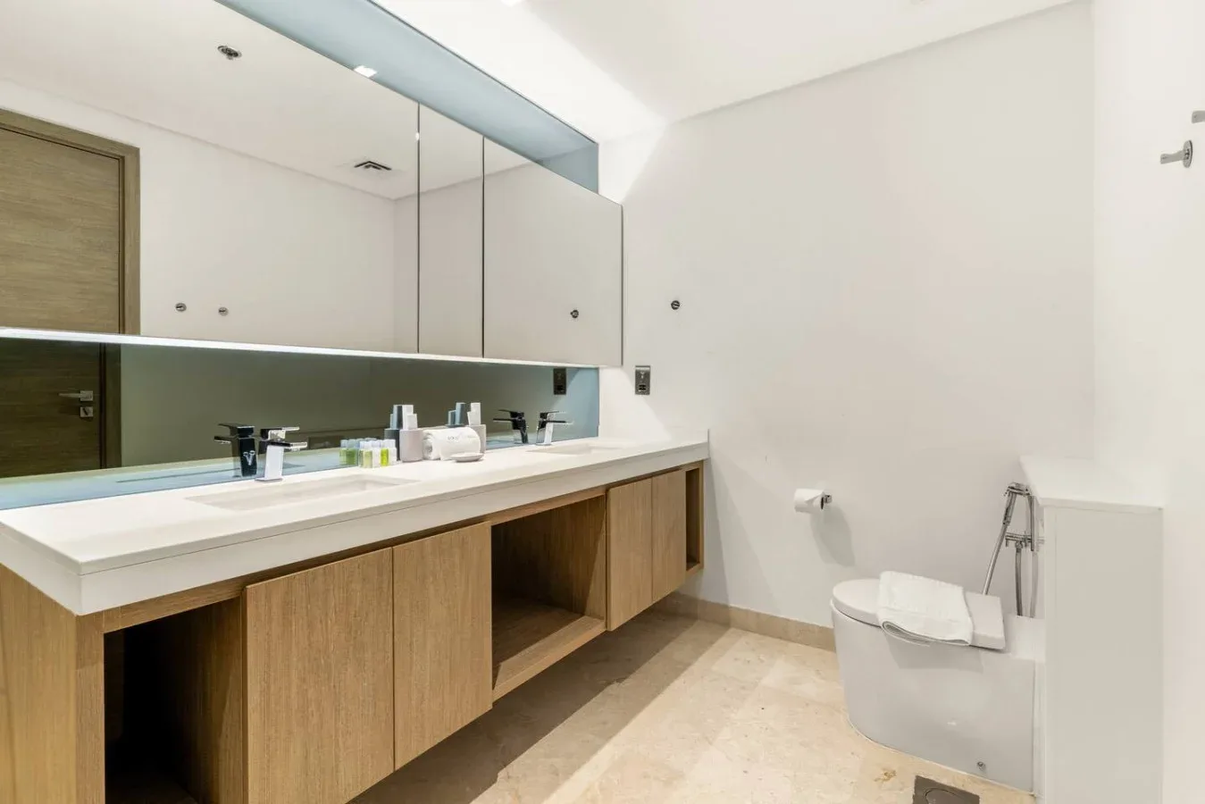 Un baño luminoso con un tocador largo, un espejo amplio y un inodoro.