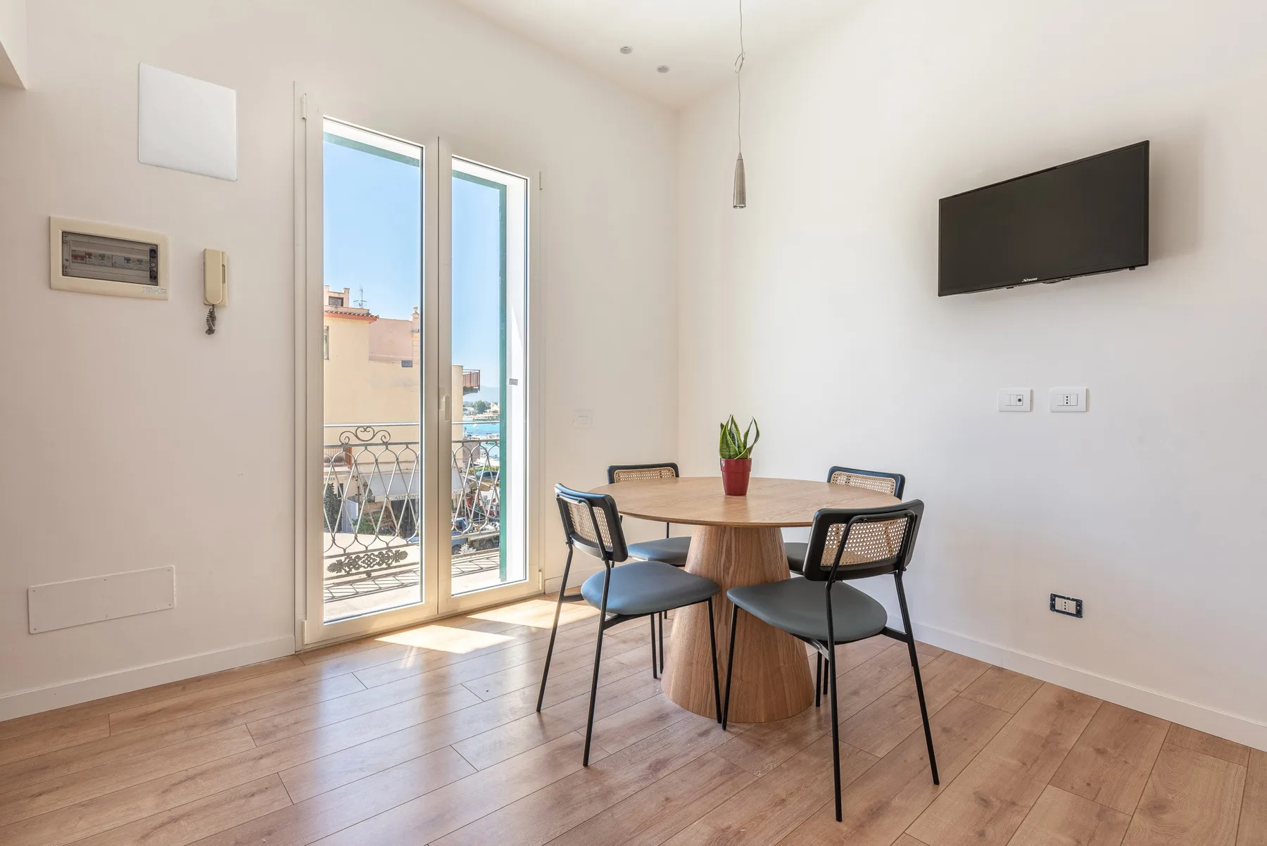 Comedor con una mesa redonda, asientos y un televisor montado en la pared.