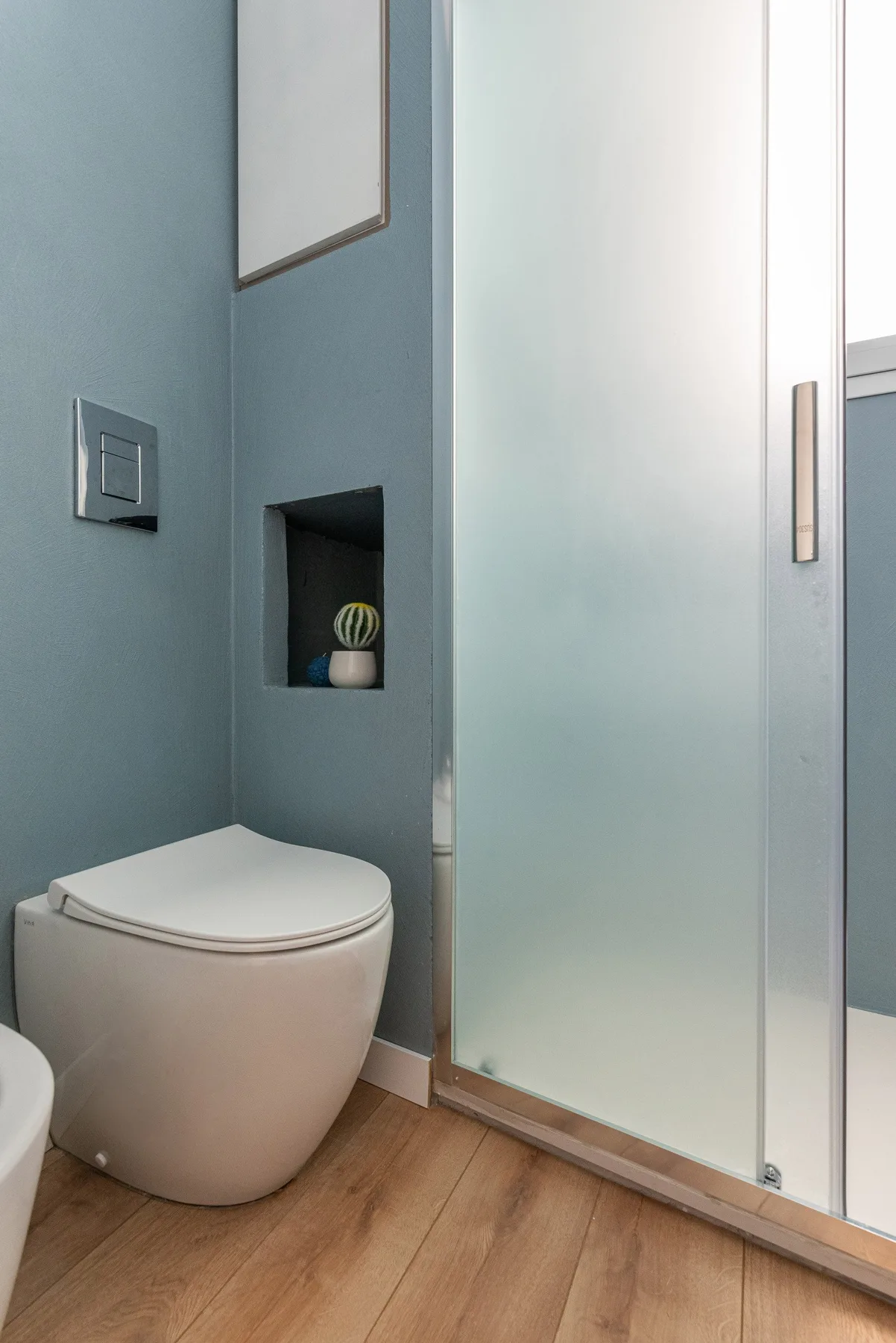 Un baño con un inodoro junto a una ducha de vidrio.