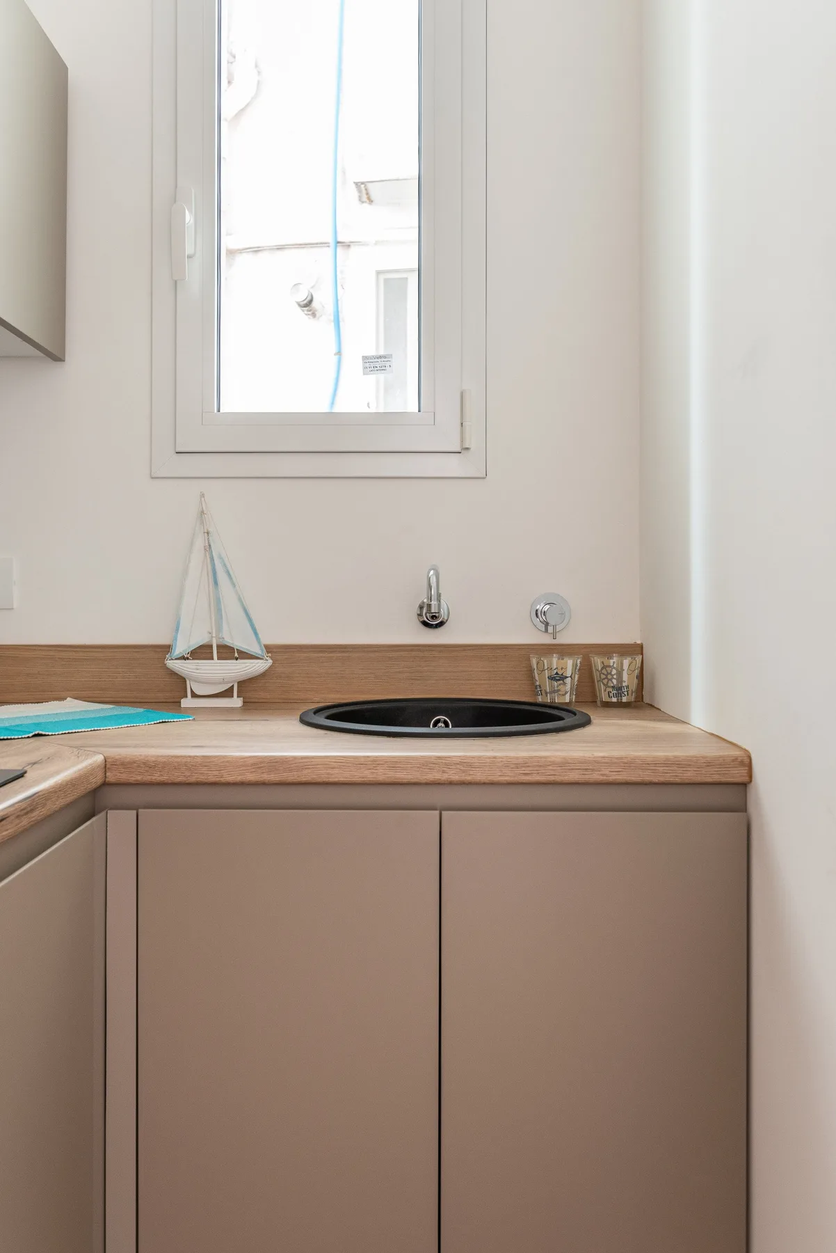 Un mueble de baño con lavabo oscuro está bajo una ventana.