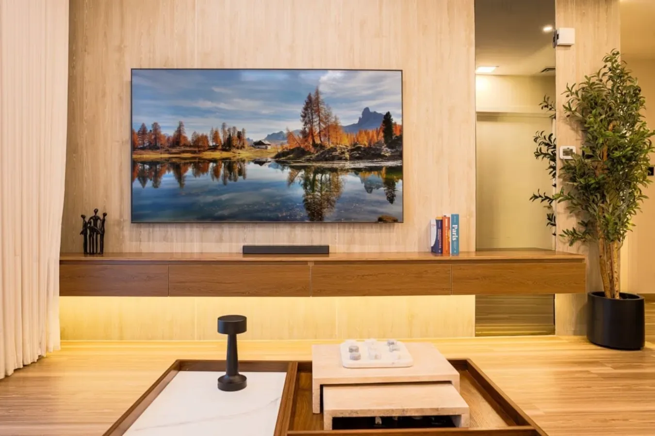 A living room with a wall-mounted television above a long wooden console.