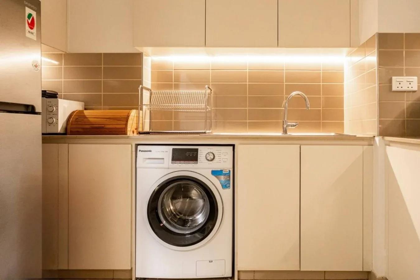 A laundry area with a washing machine, countertop, and sink.