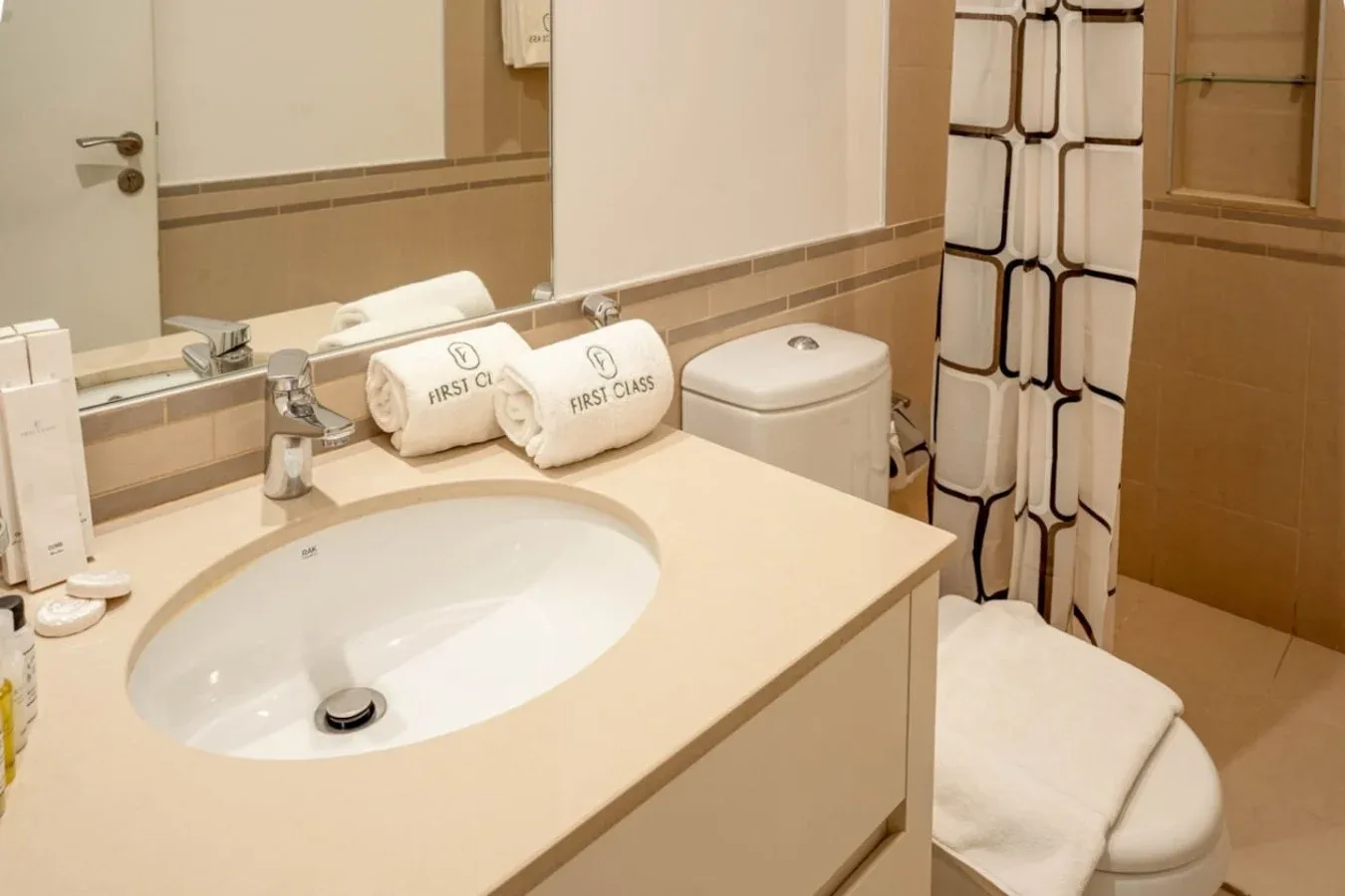 A bathroom vanity with a sink and toilet beside a patterned shower curtain.