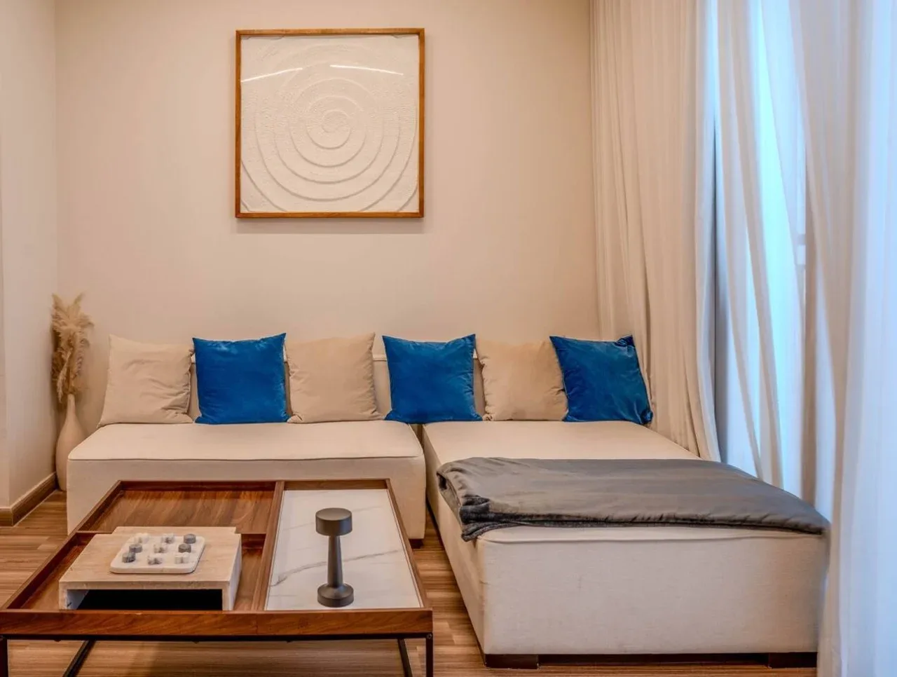 A living room with a sectional sofa, blue cushions, and a low coffee table.