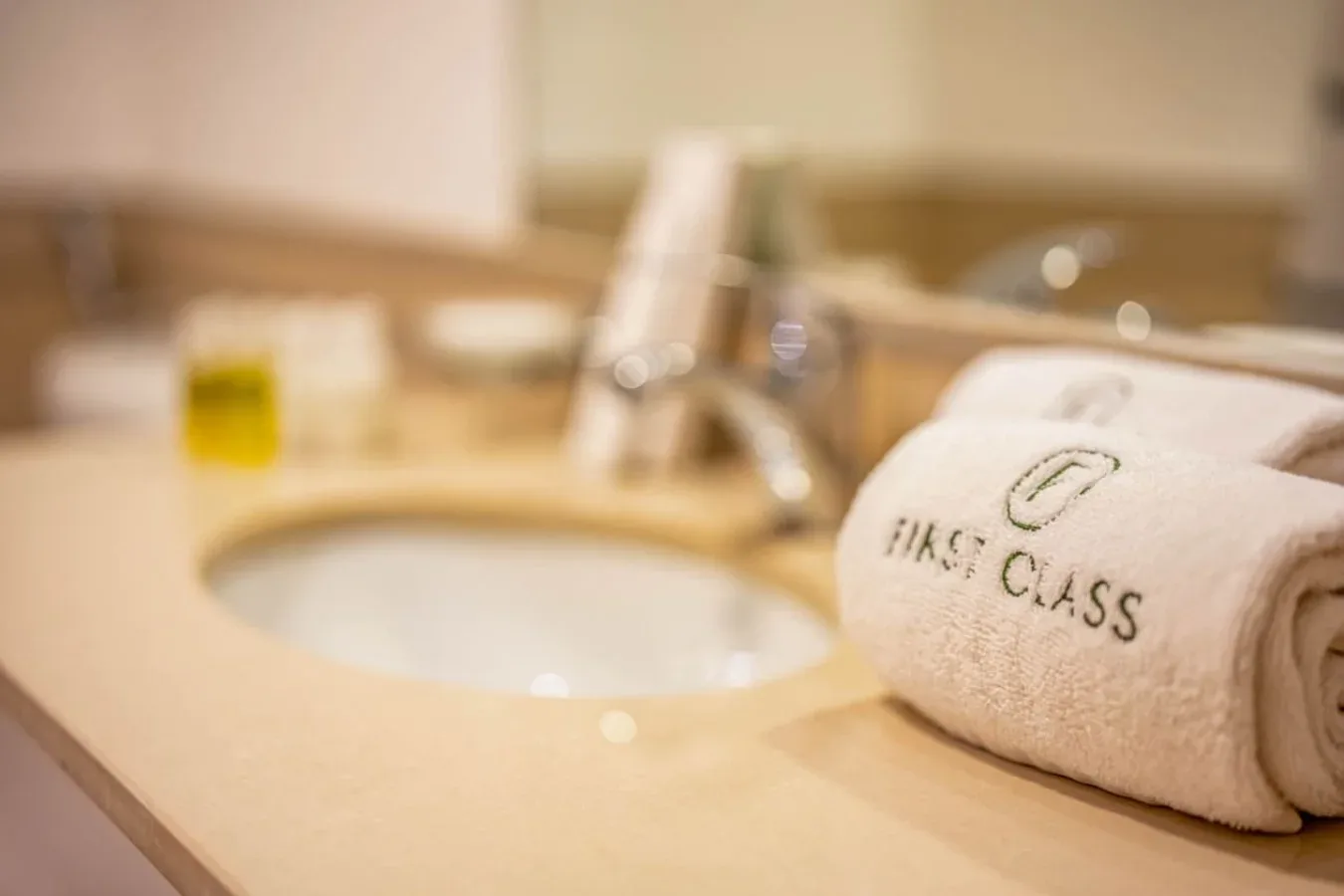 A bathroom vanity with a sink, faucet, and a rolled towel on the counter.