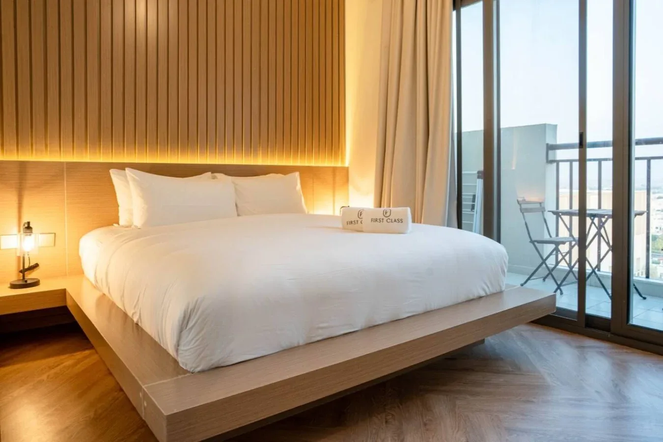 A bedroom with a neatly made bed beside floor-to-ceiling windows.