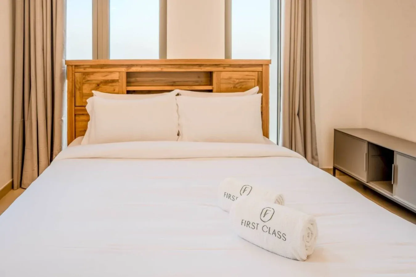 A bedroom with a neatly made bed and wooden headboard.