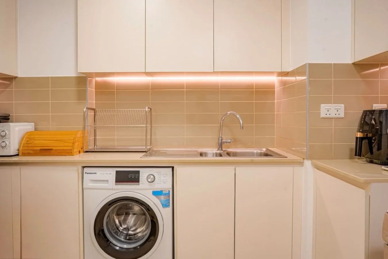 A compact kitchen with a countertop sink and washing machine.