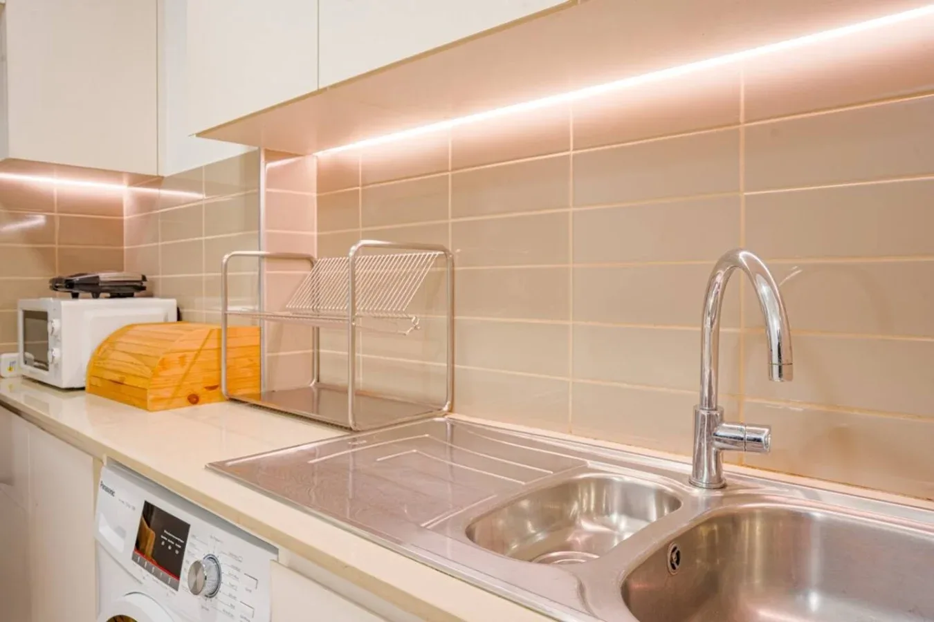 A modern kitchen counter with a sink, faucet, and small appliances.