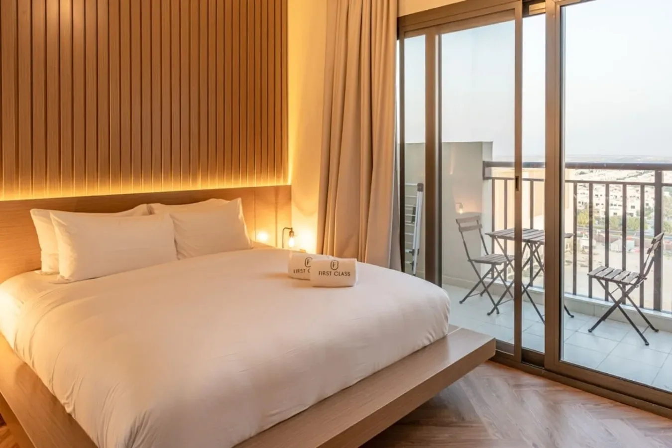 Un dormitorio con una cama bien tendida junto a puertas corredizas de vidrio que dan a un balcón.