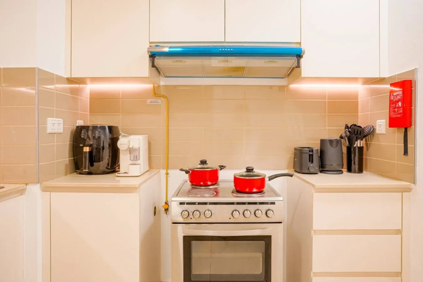 A kitchen with a stove, range hood, and countertop appliances.