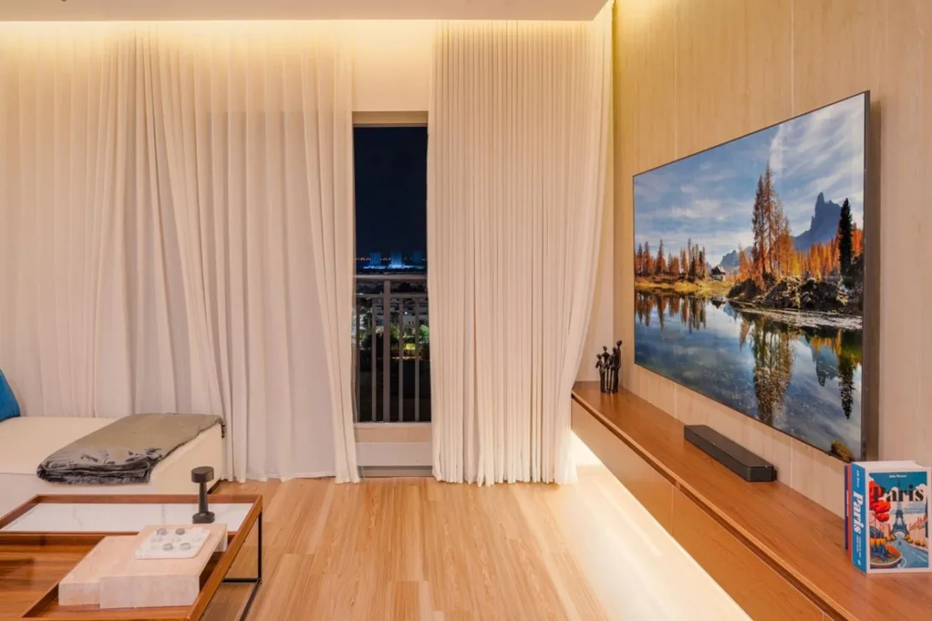 A living room with floor-length curtains and a wall-mounted television.